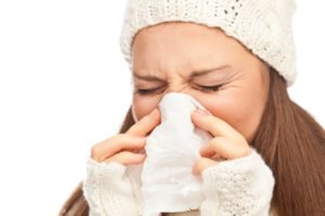 Girl in winter clothing sneezing